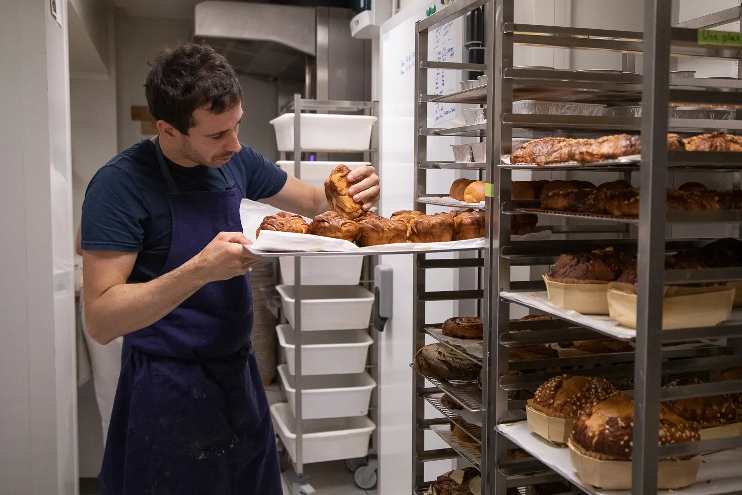 Le boulanger sortant les viennoiseries des clayettes du fournil